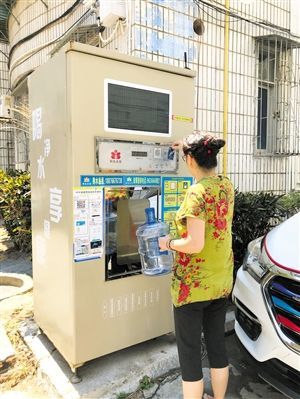 5月24日，瓊山區(qū)上丹花苑小區(qū)居民陳女士在使用共享凈水機取水。 本報記者 陳歆卓 攝